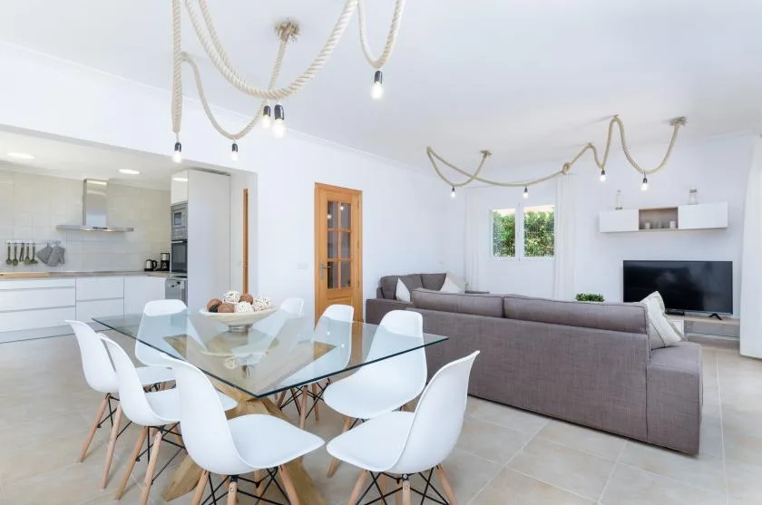 Una sala-comedor de concepto abierto con una mesa de vidrio y asientos.