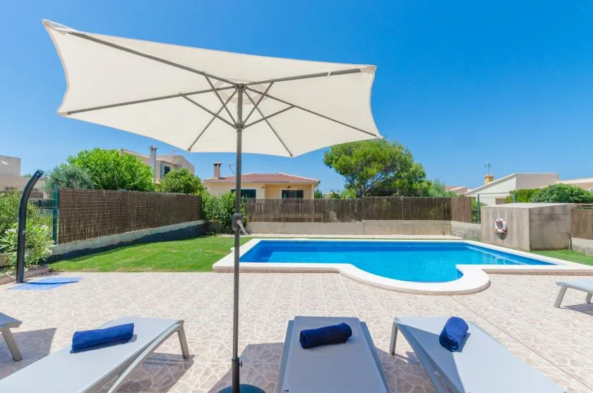 Una zona de piscina al aire libre con tumbonas bajo una gran sombrilla.