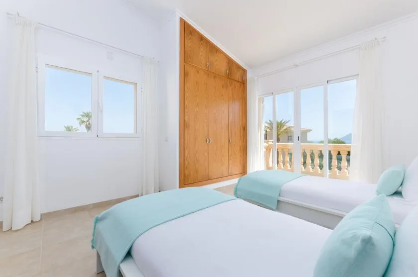 Un dormitorio luminoso con dos camas y un armario grande de madera.