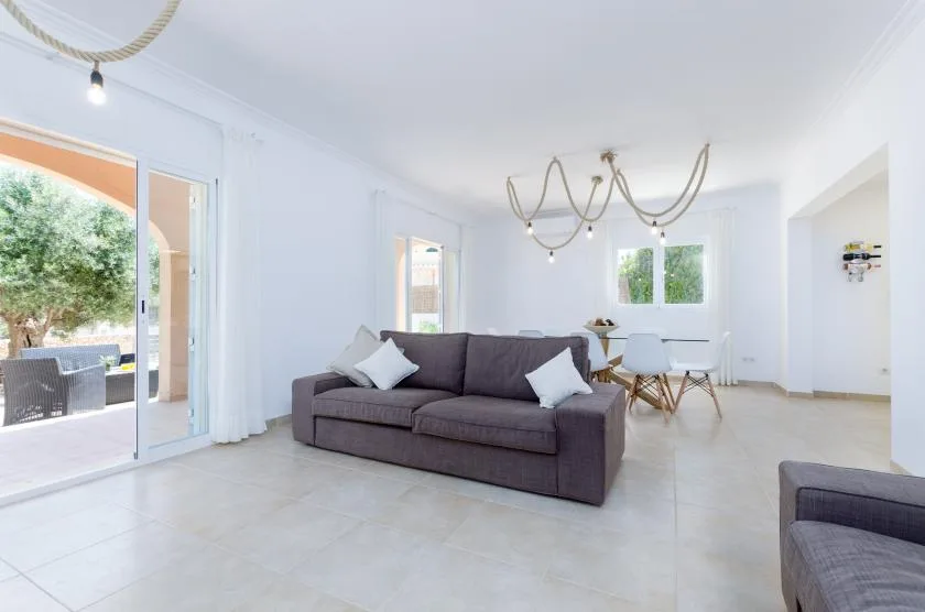 Una luminosa sala de estar y comedor con un sofá y una mesa junto a las ventanas.