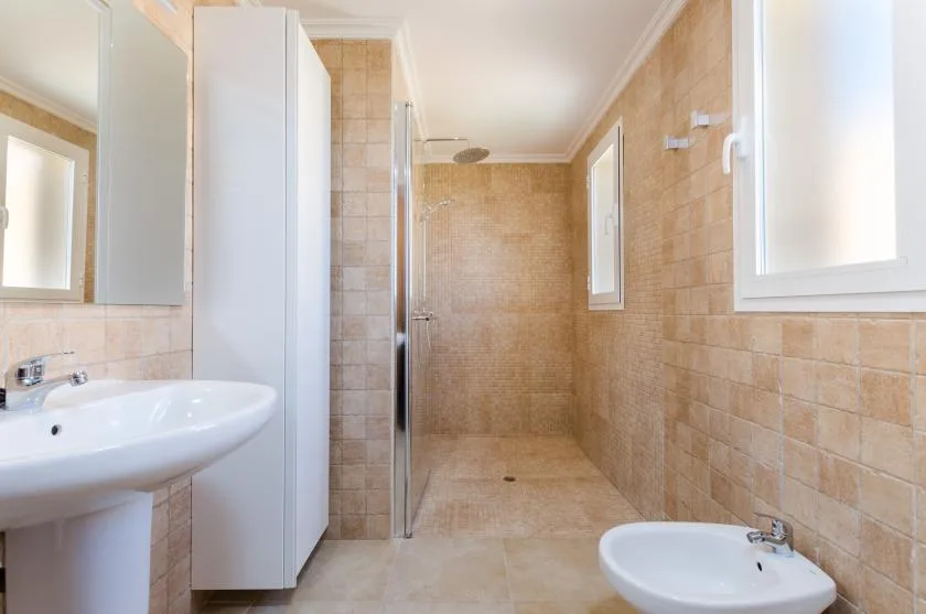 Un baño de azulejos con ducha, lavabo e inodoro.