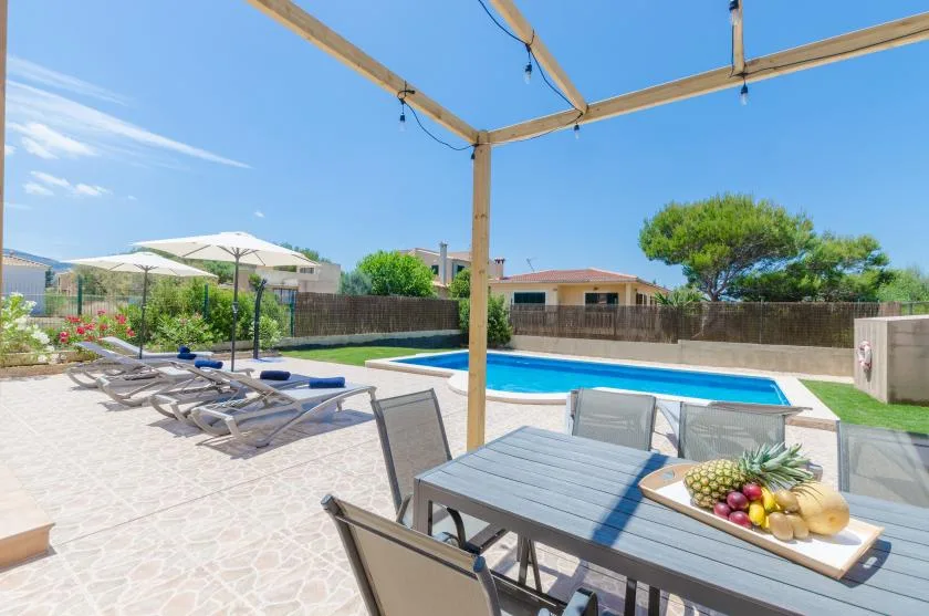 Un patio soleado con asientos al aire libre da a una piscina.