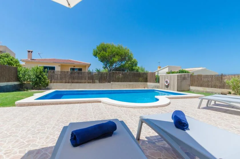Una piscina al aire libre rodeada por un patio pavimentado y asientos de descanso.