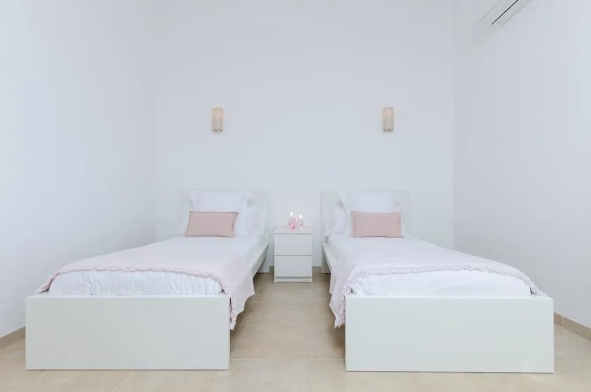 Un dormitorio luminoso con dos camas individuales y una pequeña mesita de noche.