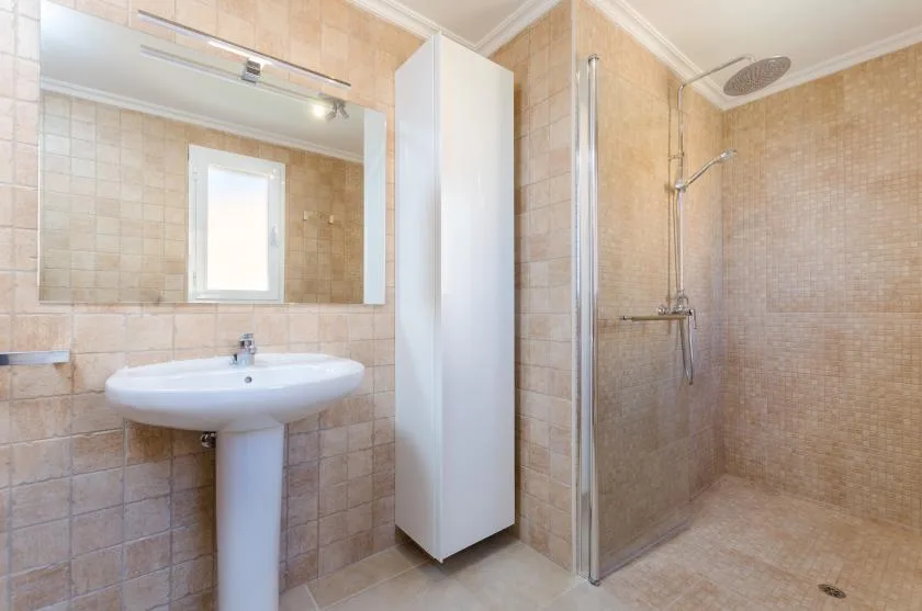 Un baño con azulejos, lavabo, espejo y ducha.