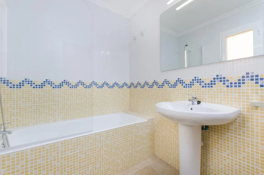 Un baño alicatado con bañera, lavabo y un gran espejo de pared.