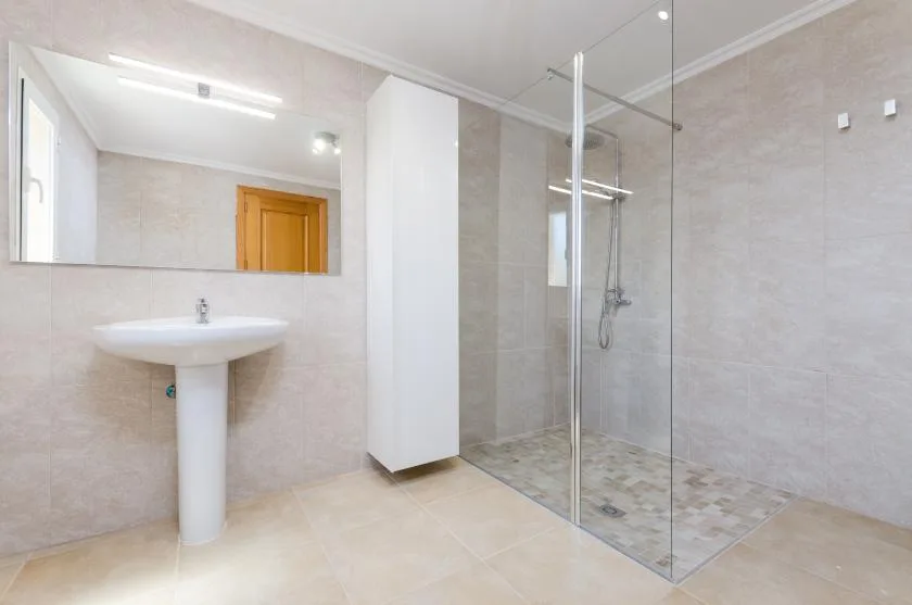 Un baño luminoso con lavabo de pedestal y ducha de vidrio.