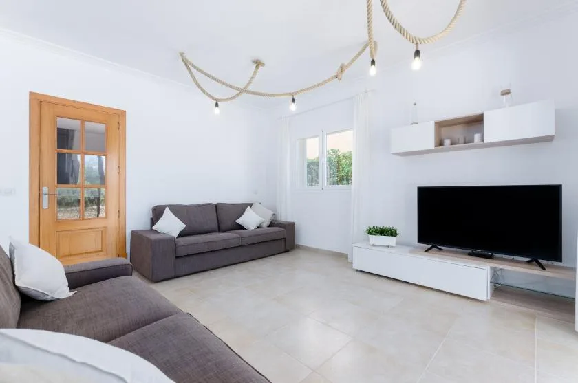 Una sala luminosa con asientos, un televisor y paredes blancas.