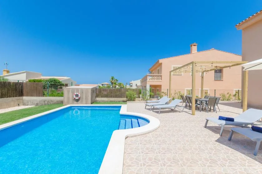 Una piscina junto a un patio pavimentado con asientos al aire libre.