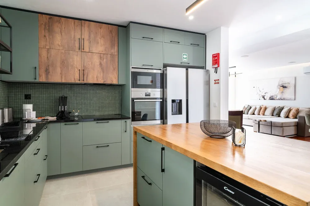 A modern kitchen with a wooden island opens onto a living area.