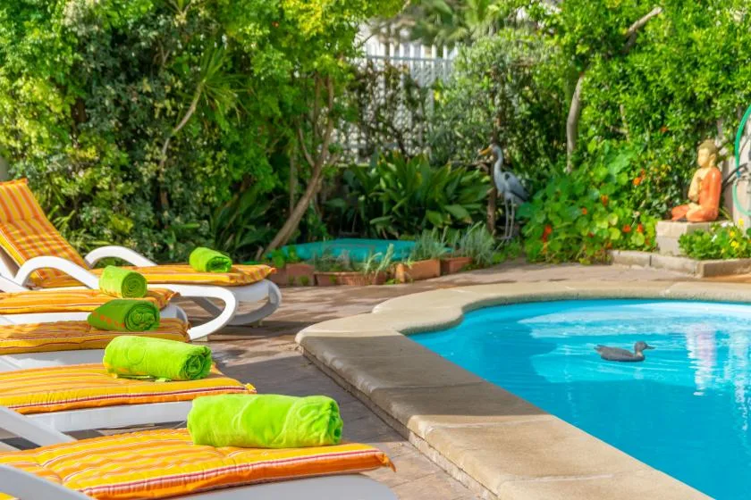 Poolside lounge area with striped sunbeds beside a blue swimming pool.