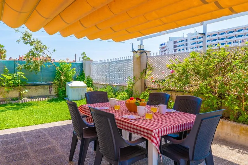 An outdoor dining area with a table beneath an orange awning.