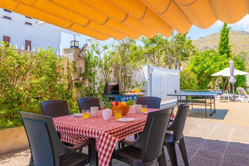 An outdoor dining area with a checkered tablecloth and seating beneath an orange awning.