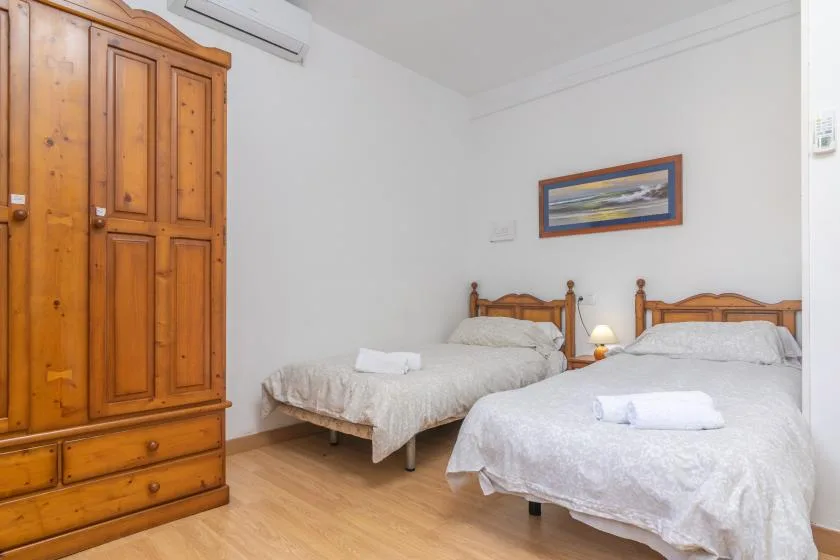 A bedroom with two beds, wooden furniture, and a framed picture on the wall.