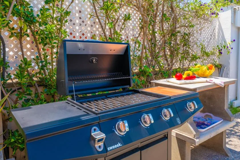 An outdoor cooking area with an open grill and a counter of vegetables.