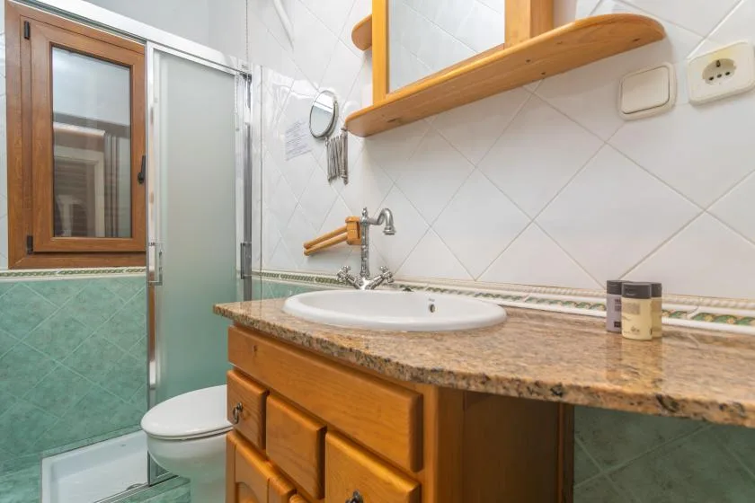 A tiled bathroom with a sink vanity and frosted glass shower screen.