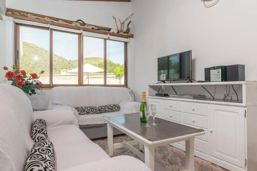 A bright living room with seating, a television, and a coffee table.