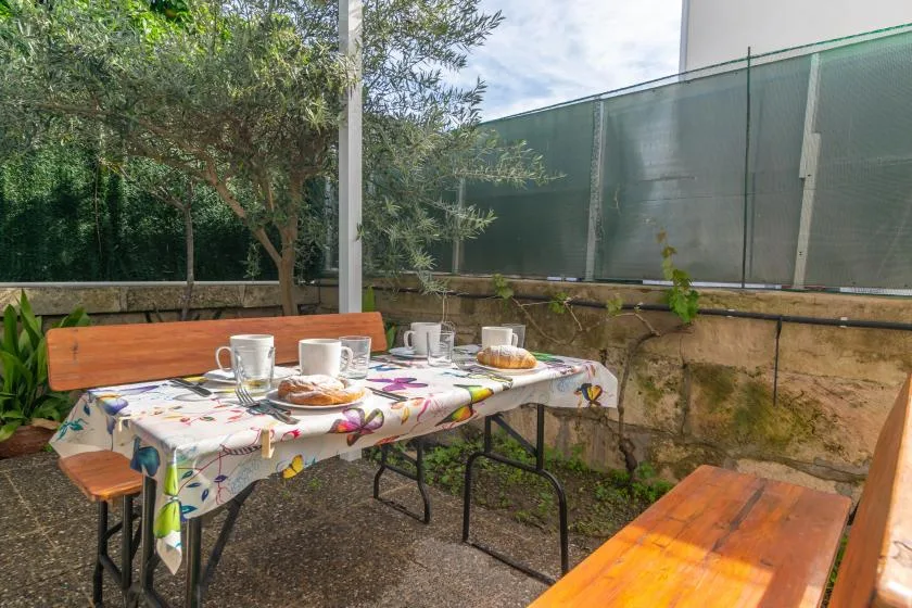 An outdoor dining area with a table set with cups and plates.