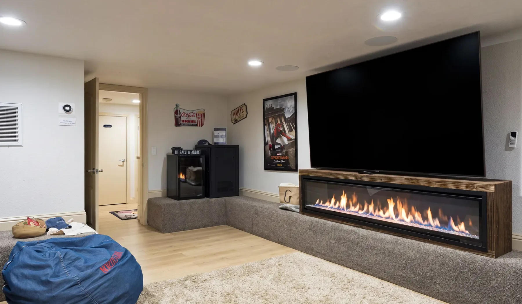 Una sala de entretenimiento en el sótano tiene un televisor grande sobre una chimenea lineal.