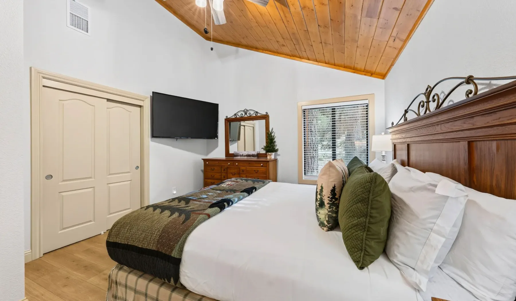 Un dormitorio con una cama grande, cabecero de madera y techo inclinado de madera.
