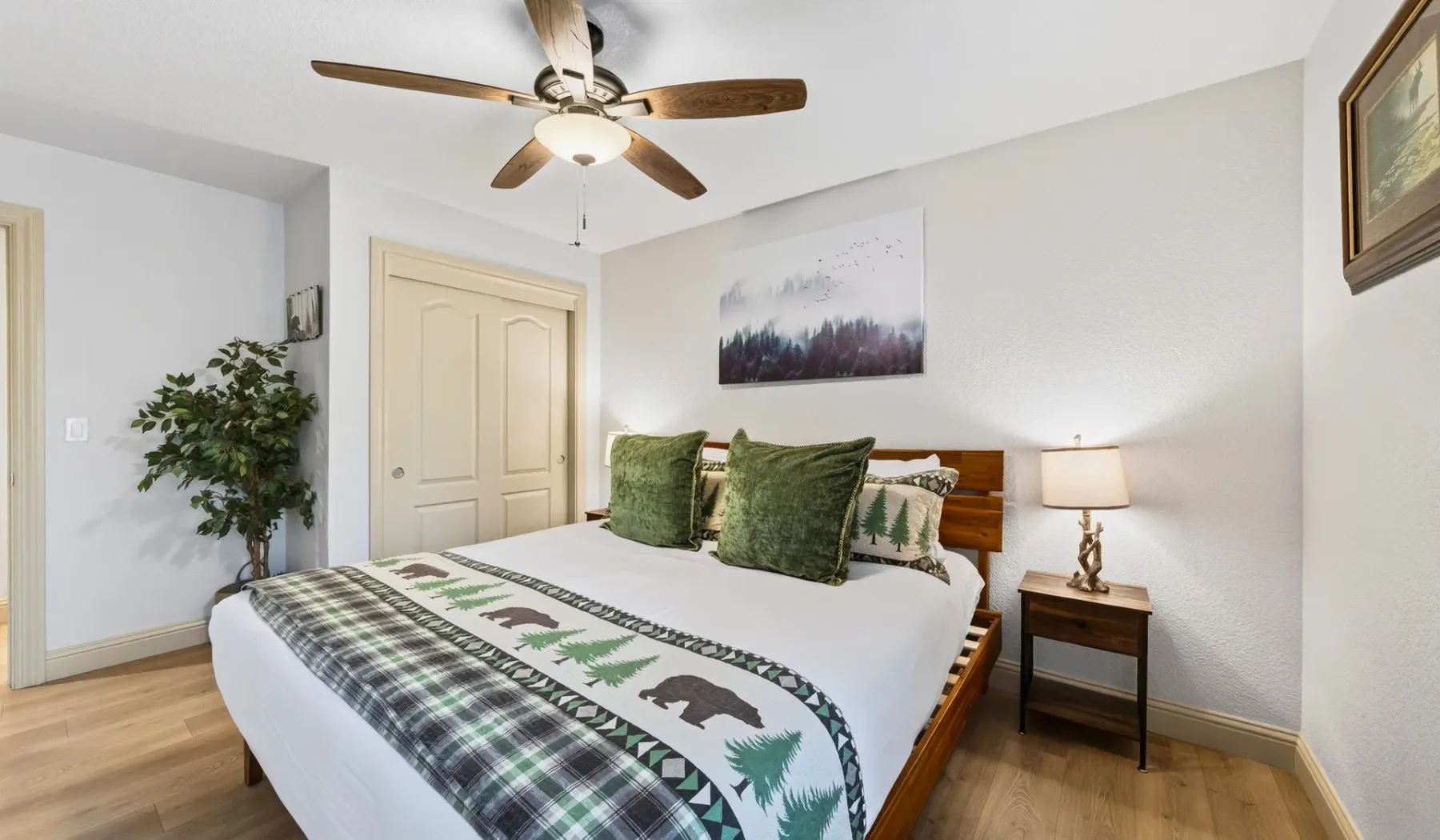 Un dormitorio con una cama tendida, almohadas verdes y un ventilador de techo.
