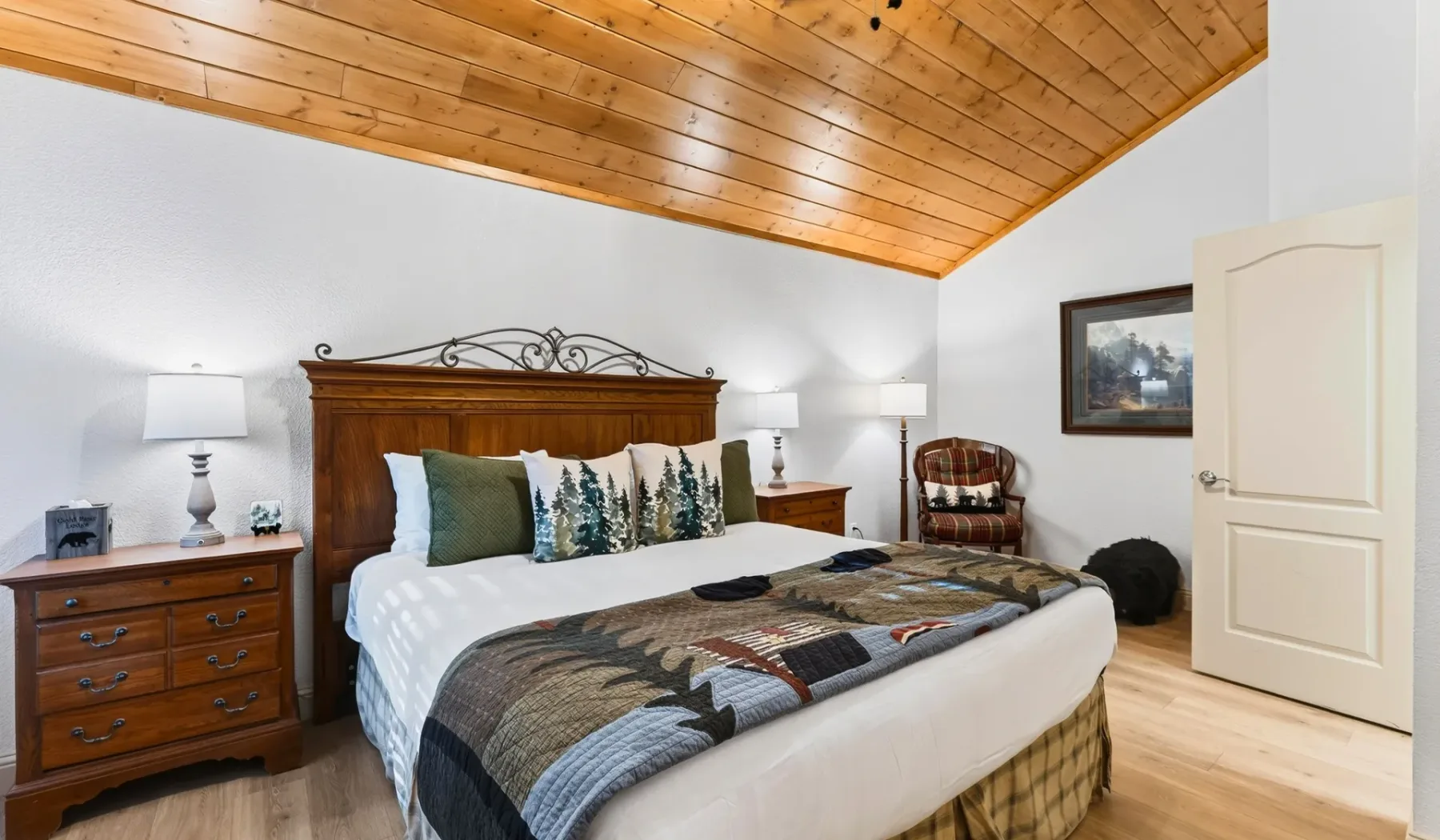 Un dormitorio con una cama grande, mesitas de noche y techo de madera.