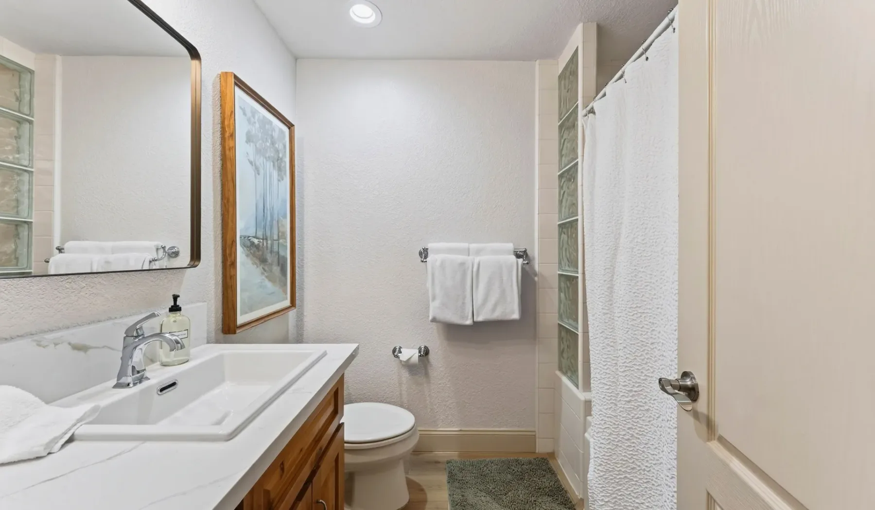 Un baño con lavabo, inodoro y ducha con cortina.