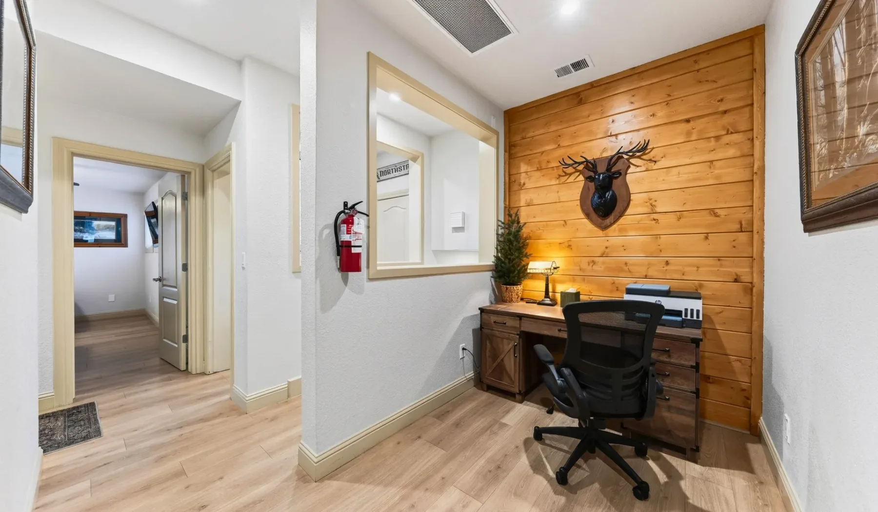 Una pequeña oficina con escritorio y silla junto a una pared revestida de madera.
