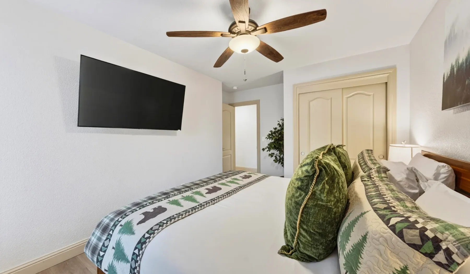 Un dormitorio con una cama, ropa de cama estampada y un televisor en la pared.