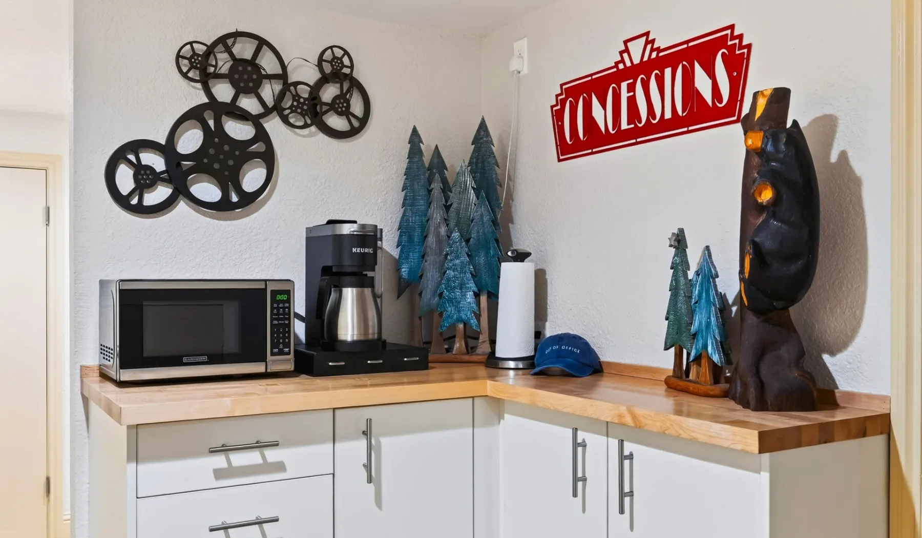 Una encimera de cocina con microondas, cafetera y figuras decorativas de árboles.
