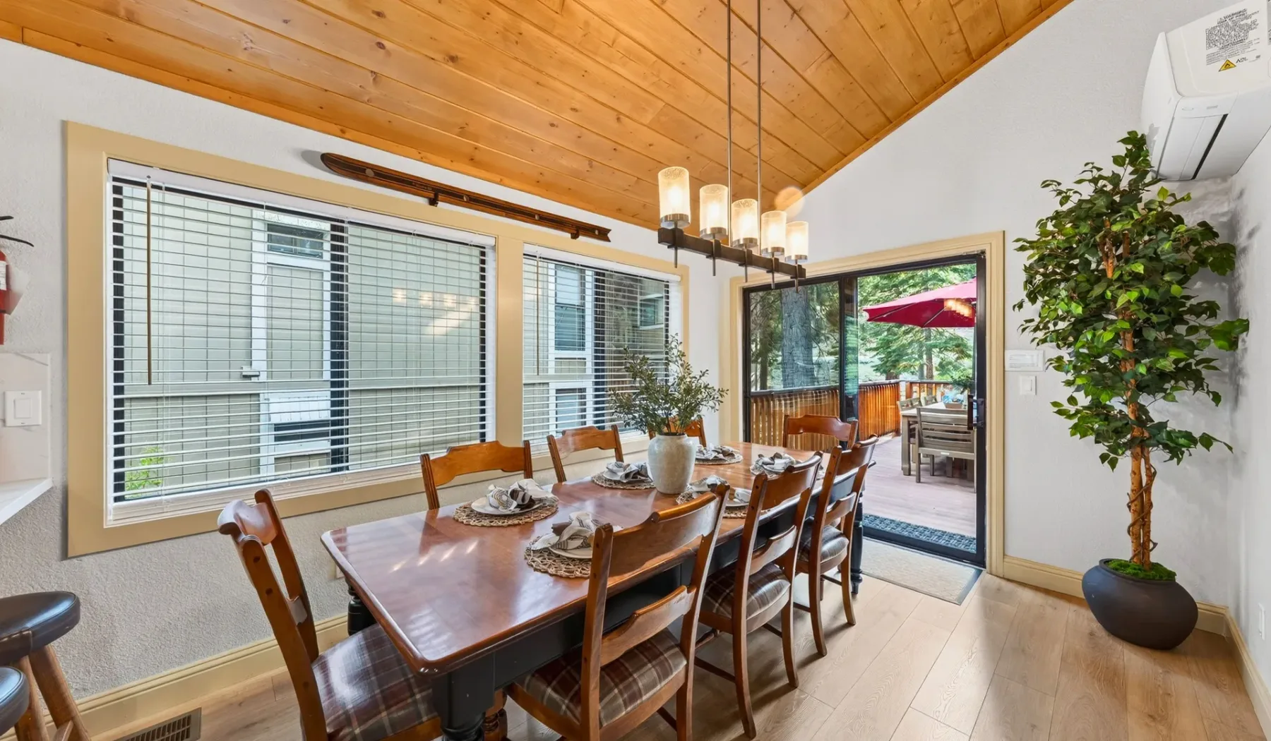Comedor con mesa de madera, sillas y ventanas que dan a un patio.