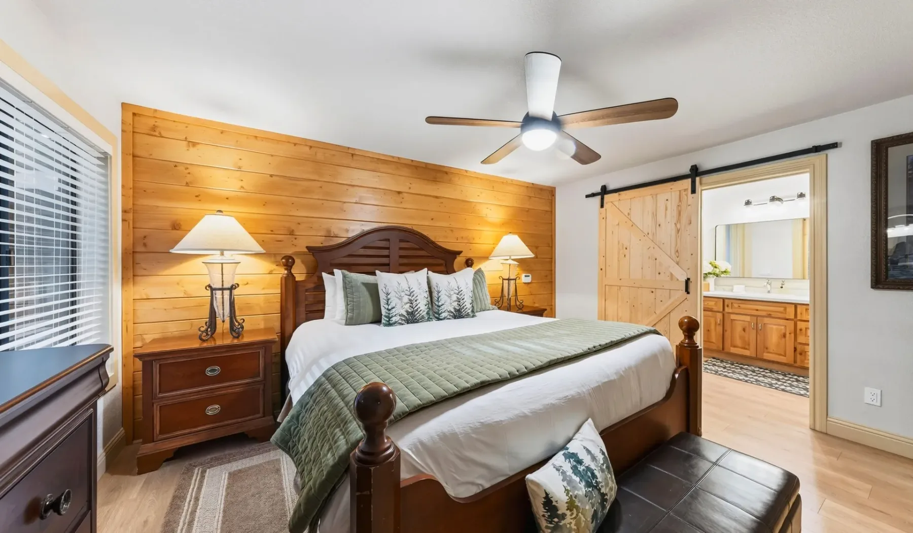 Un dormitorio con cama, pared revestida de madera y puerta corrediza tipo granero.
