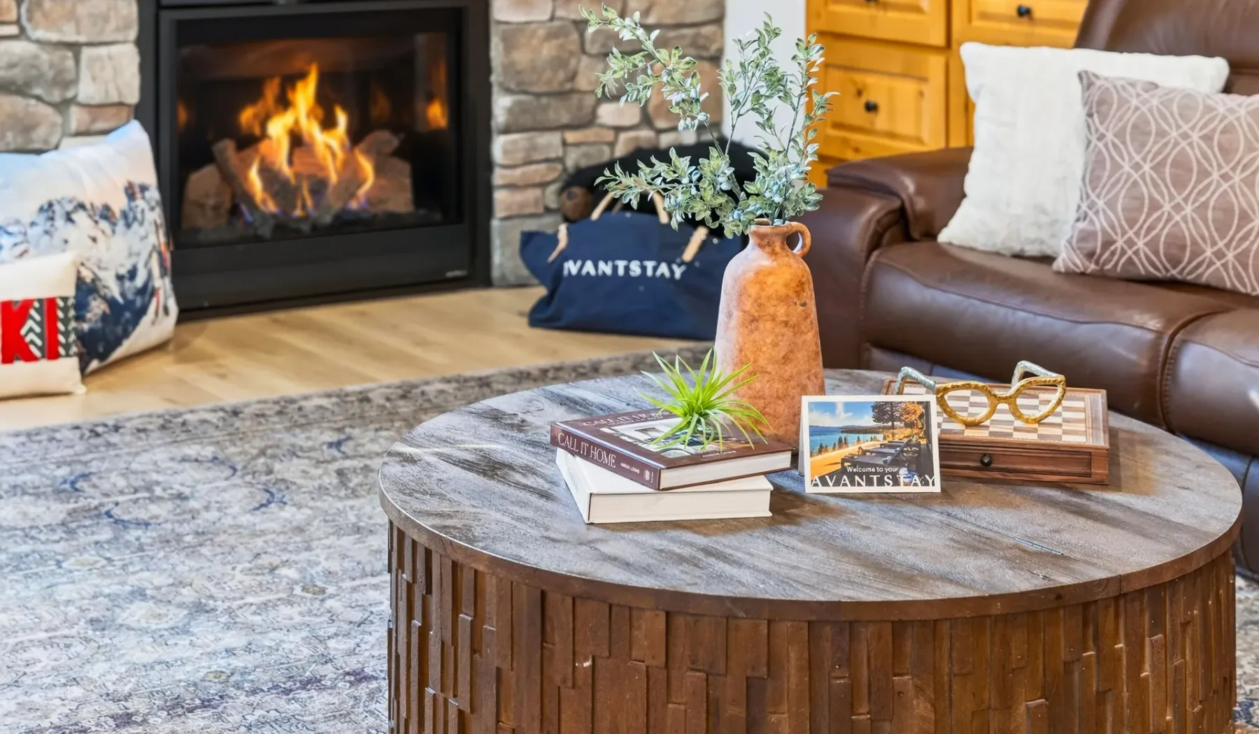 Una sala de estar con una mesa de centro redonda, asientos y una chimenea encendida.