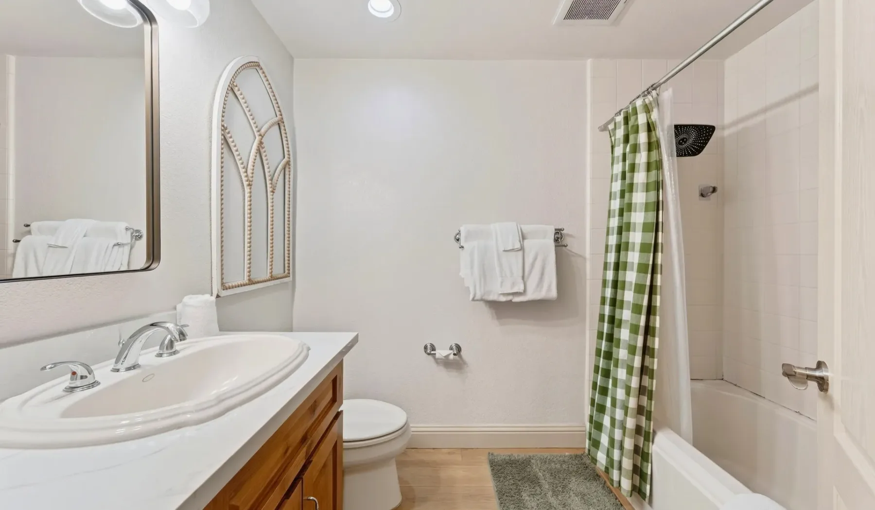 Un baño con lavabo, inodoro y bañera detrás de una cortina de ducha a cuadros.