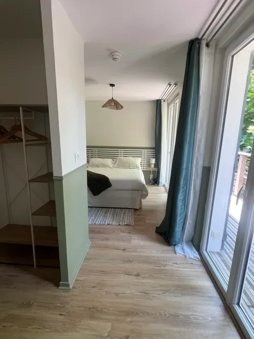 Moderna habitación de hotel con vistas al lago, cama, puertas correderas que dan al balcón y mobiliario contemporáneo.