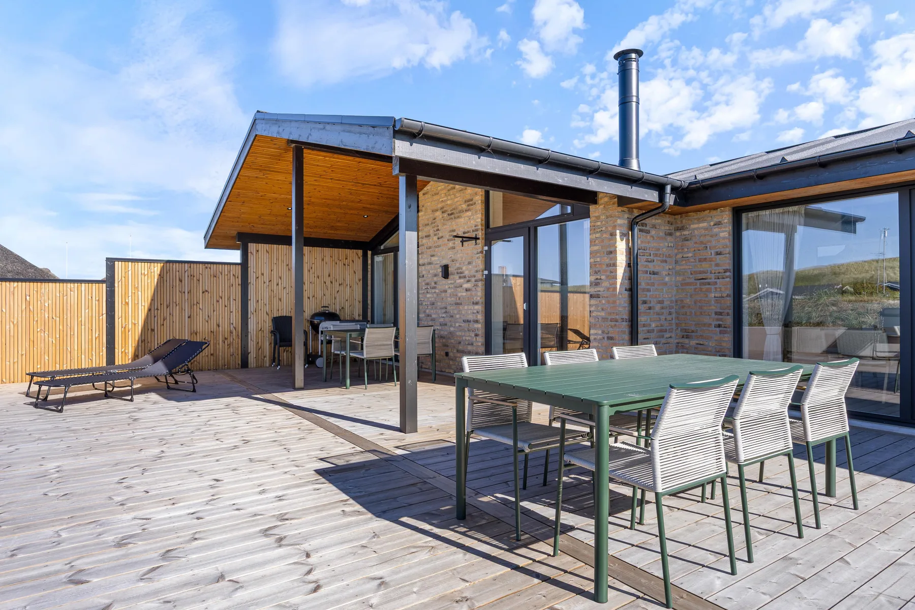 Patio con muebles de comedor al aire libre junto a una casa moderna de ladrillo.