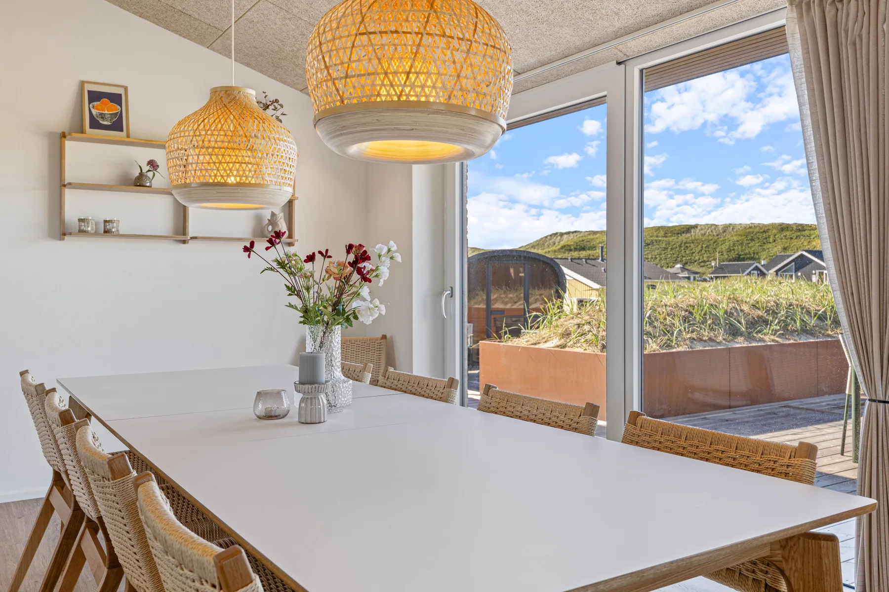 Un comedor luminoso con una mesa larga junto a grandes ventanales con vistas a la vegetación.