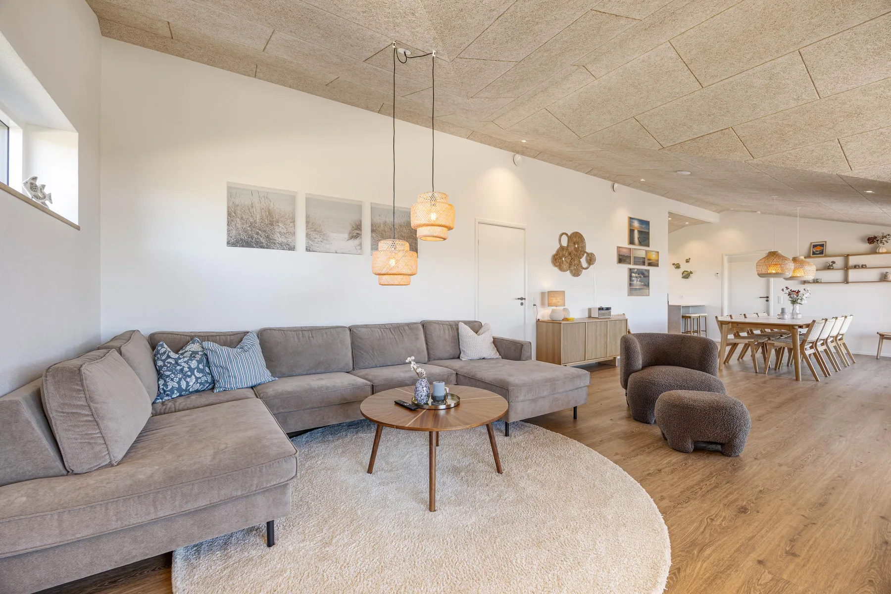 Espacio diáfano de sala y comedor con asientos seccionales y una mesa de centro redonda.