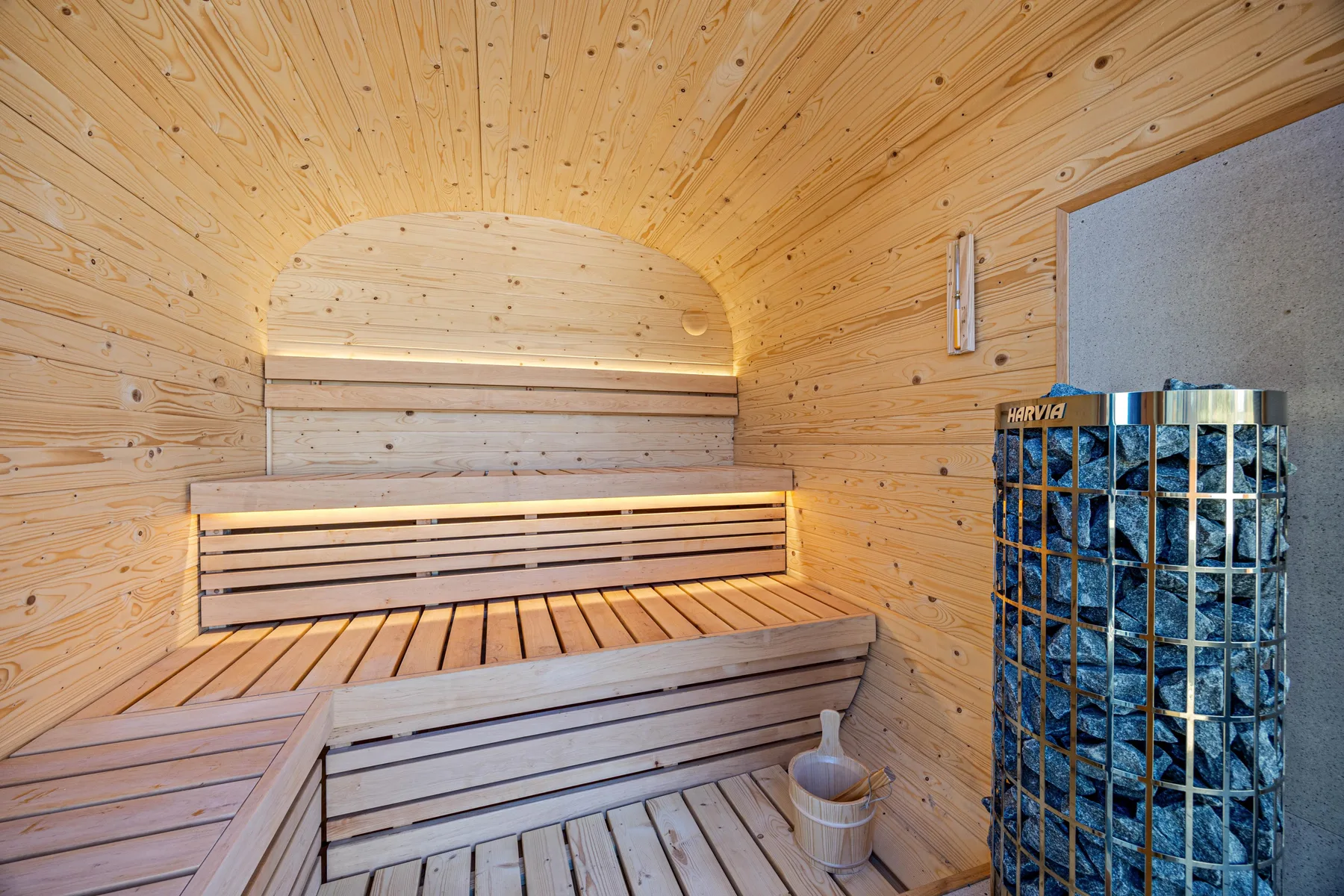 Una sauna de madera con bancos escalonados y una estufa.