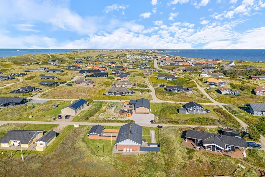 Vista aérea de un barrio costero con casas dispersas y caminos.