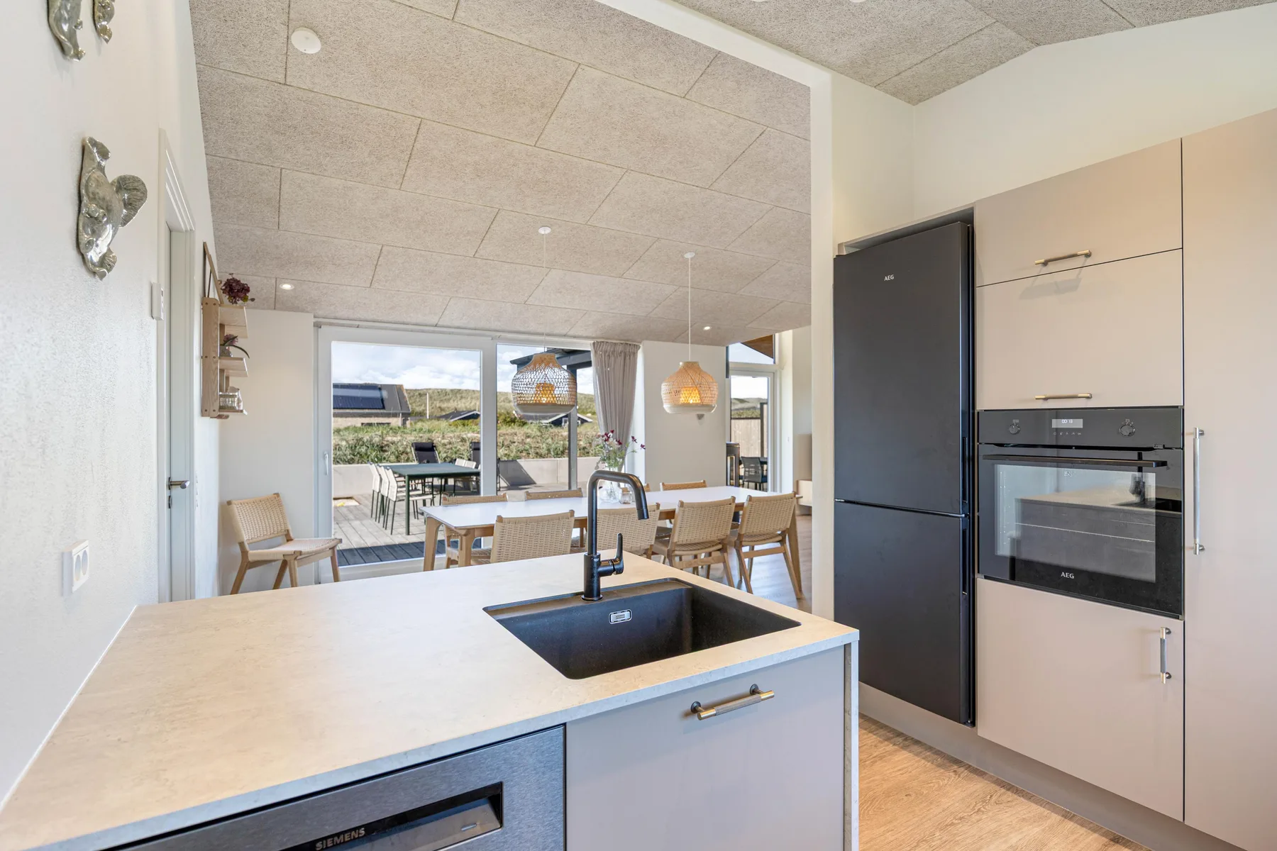Una cocina luminosa se abre a un comedor con grandes ventanas.