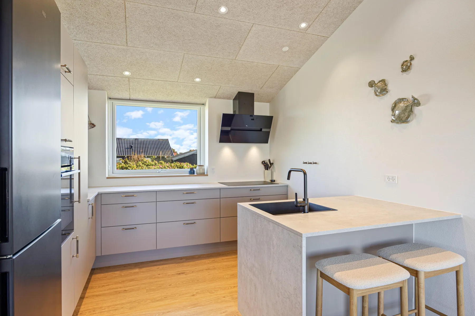 Una cocina moderna y luminosa con una isla central y una ventana con vista a los tejados.