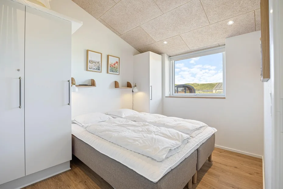 Un dormitorio luminoso con una cama bajo una ventana amplia.