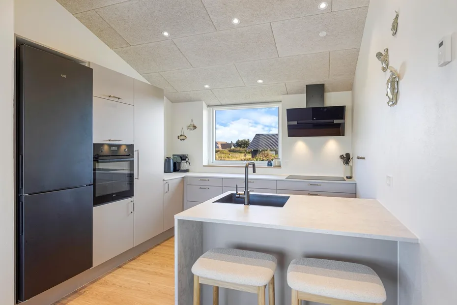 Una cocina moderna y luminosa con una gran isla y una ventana sobre la encimera.