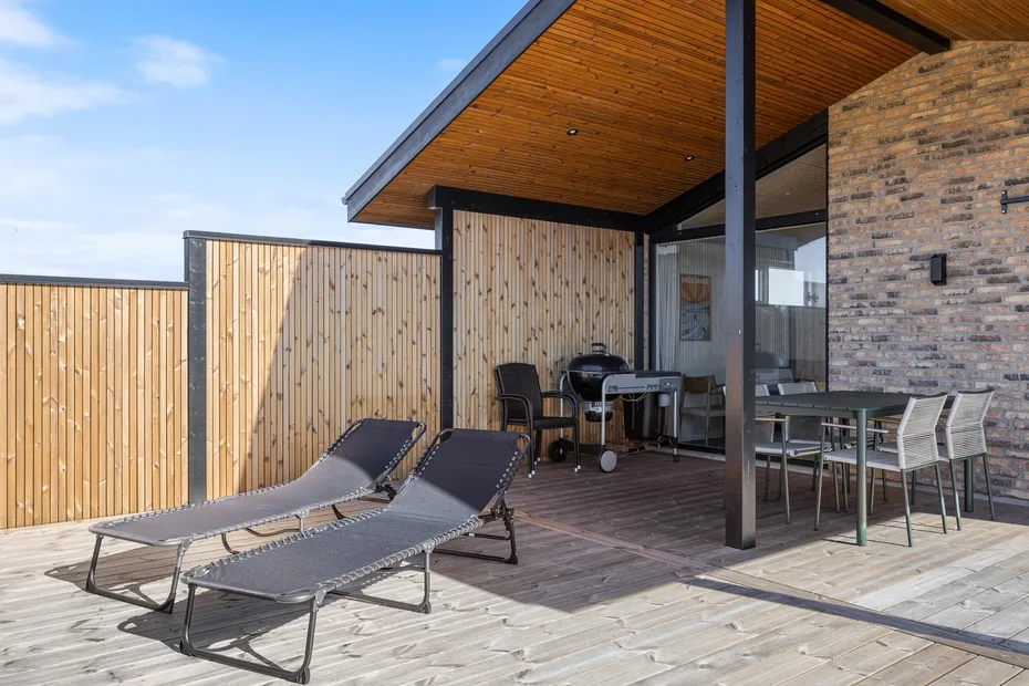 Una terraza exterior con asientos reclinables y una zona de comedor cubierta.