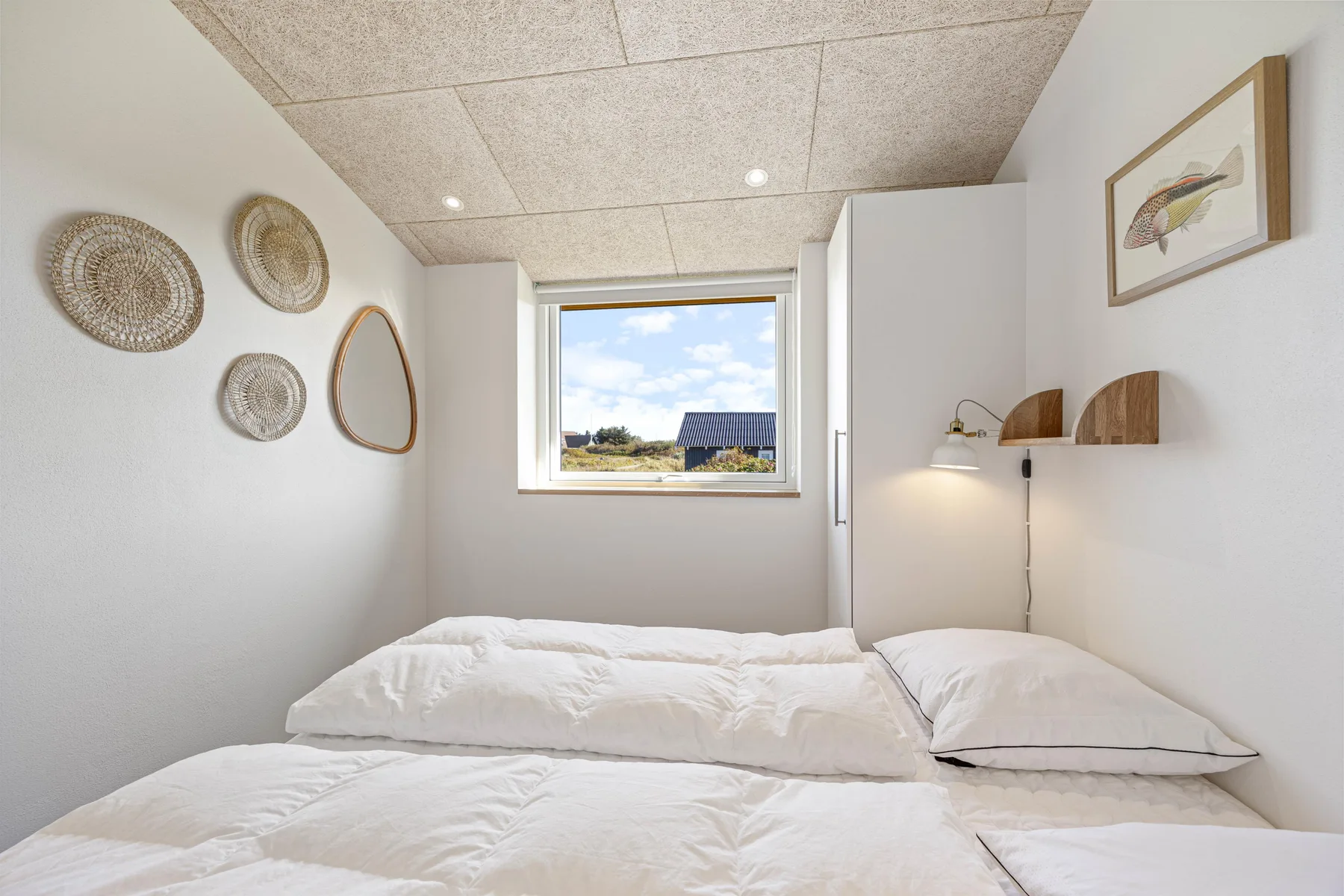 Un dormitorio luminoso con ropa de cama blanca y una ventana con vistas al paisaje.