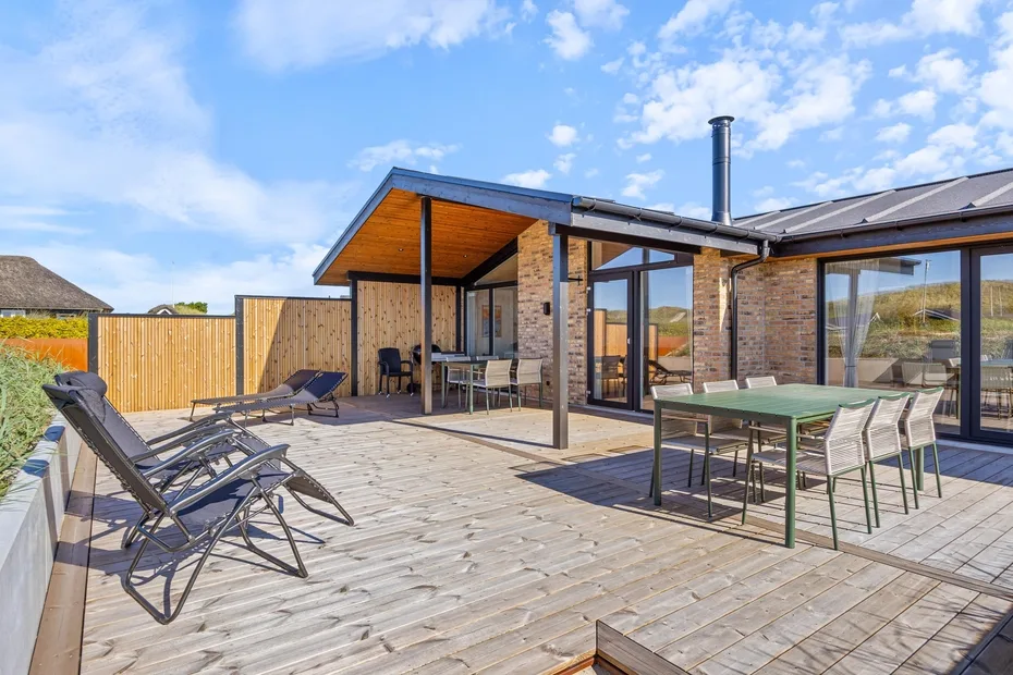 Una amplia terraza de madera con asientos al aire libre junto a una casa moderna.