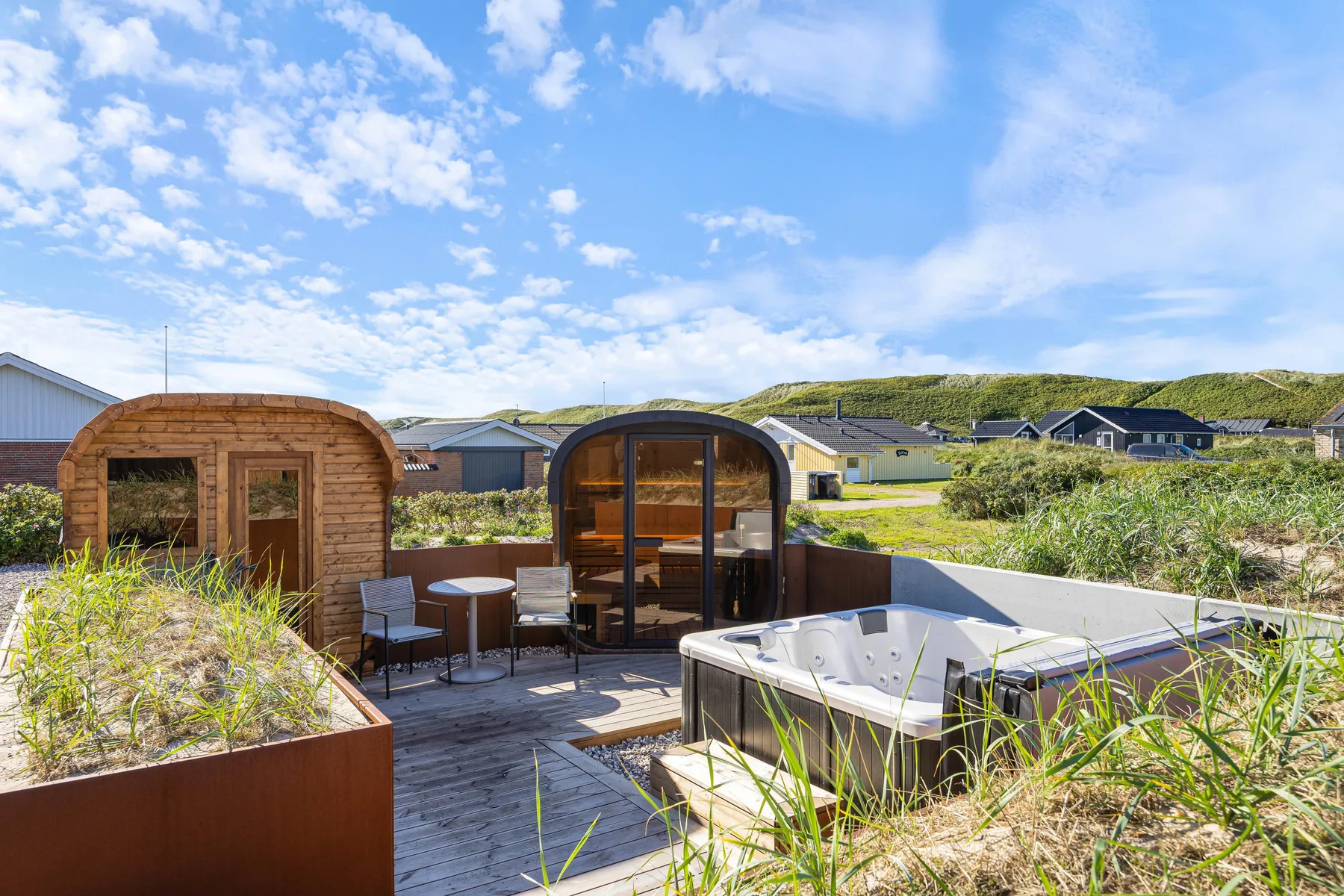 Una terraza exterior tiene una bañera de hidromasaje, asientos y una pequeña estructura de madera.