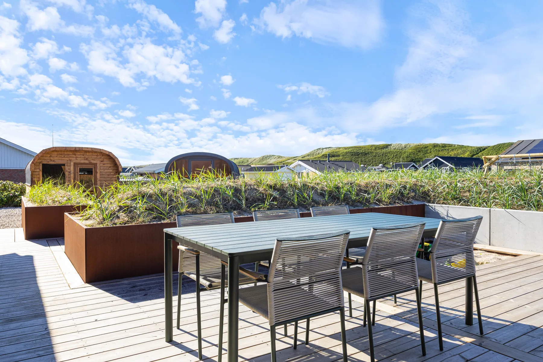 Comedor al aire libre con mesa y sillas sobre una terraza de madera.