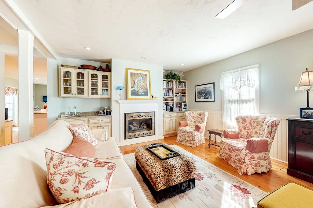 A bright living room with floral seating around a low coffee table.